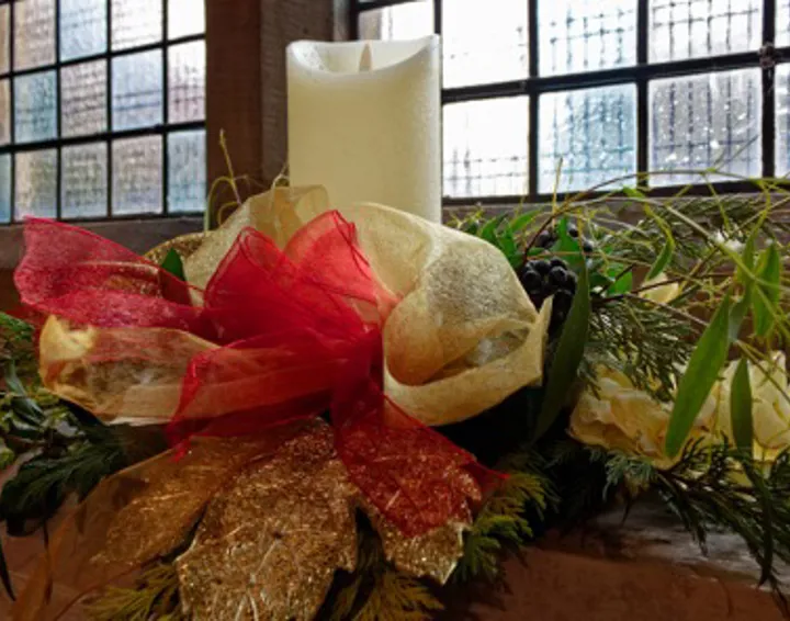 Candle, ribbon and foliage arrangement on church window sill.